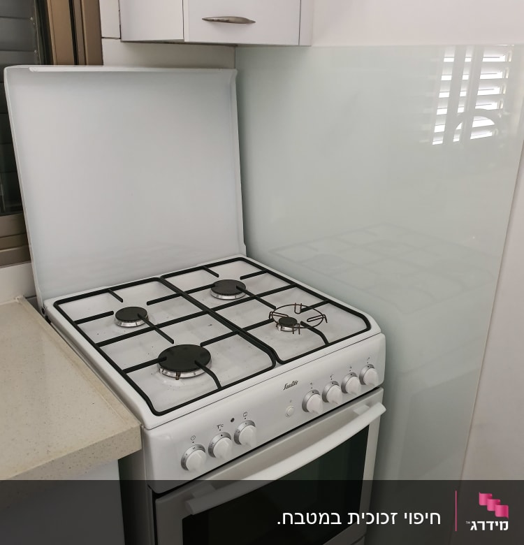 מגן זכוכית שקוף מאחורי כיריים במטבח